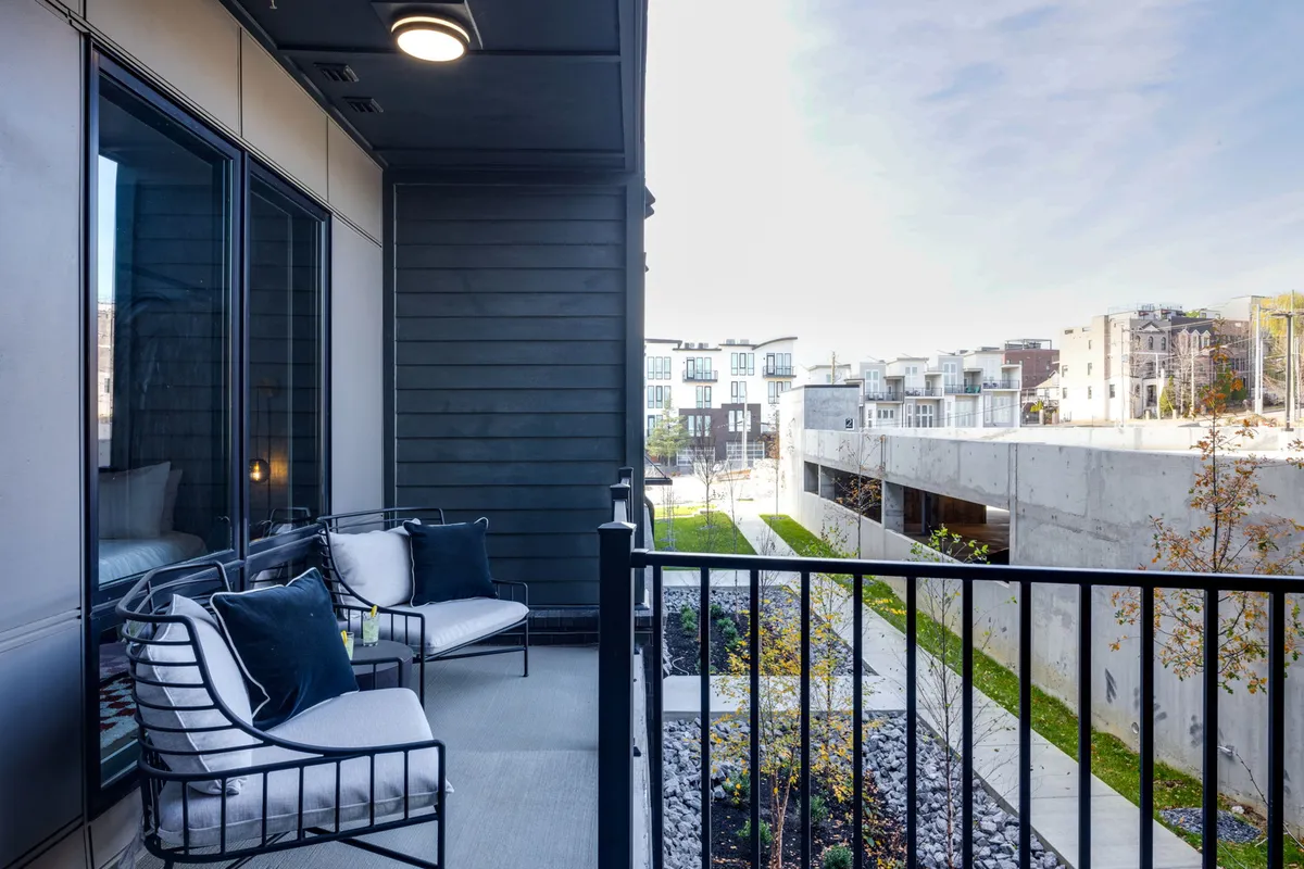 A serene view from a modern balcony featuring comfortable seating and a cityscape backdrop. The foreground invites relaxation while the skyline connects to the urban adventure outside.